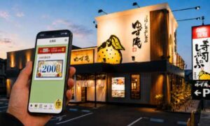 ゆず庵の外観前で公式アプリのクーポン情報を確認する場面