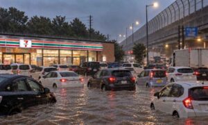 豪雨で冠水したコンビニ駐車場と道路で、多くの車やトラックが動けず立ち往生している様子